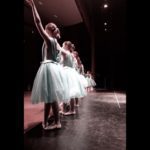 ballet dancers standing in a row on stage